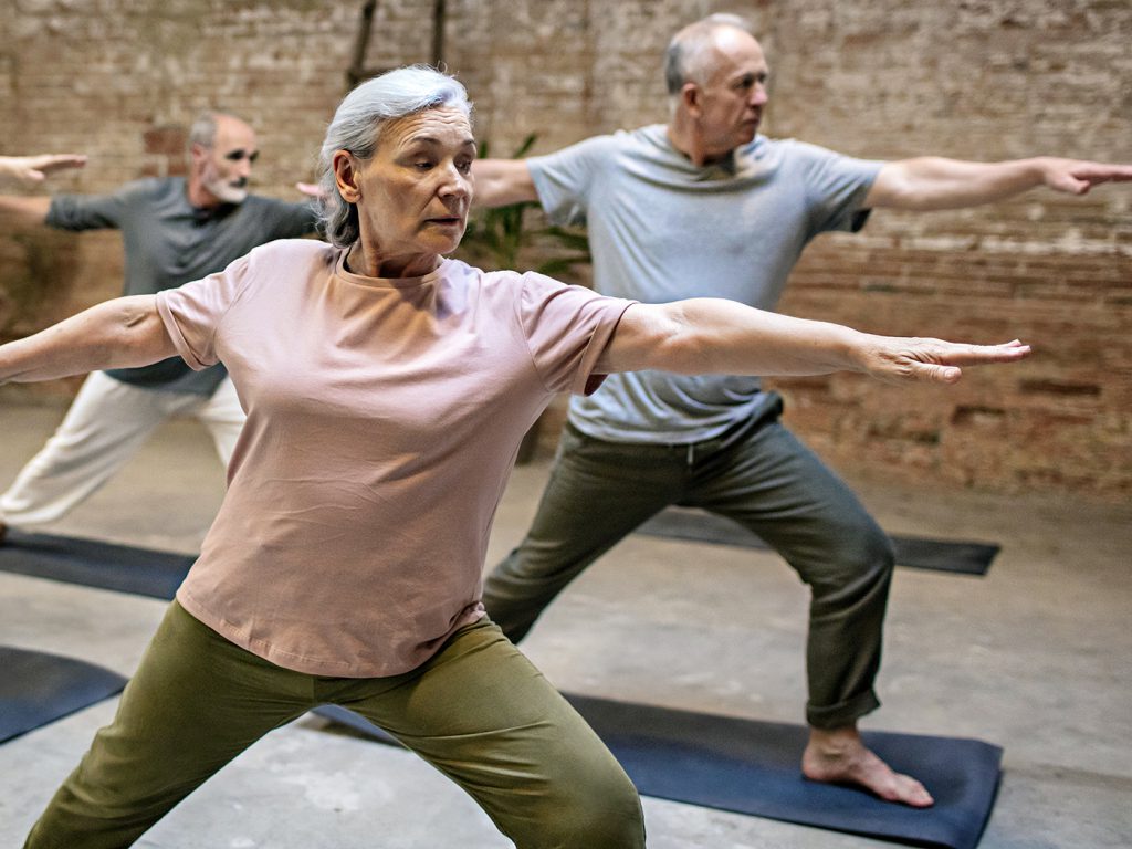 class of older adults doing warrior two pose