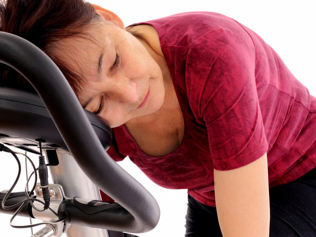 tired woman on elliptical machine