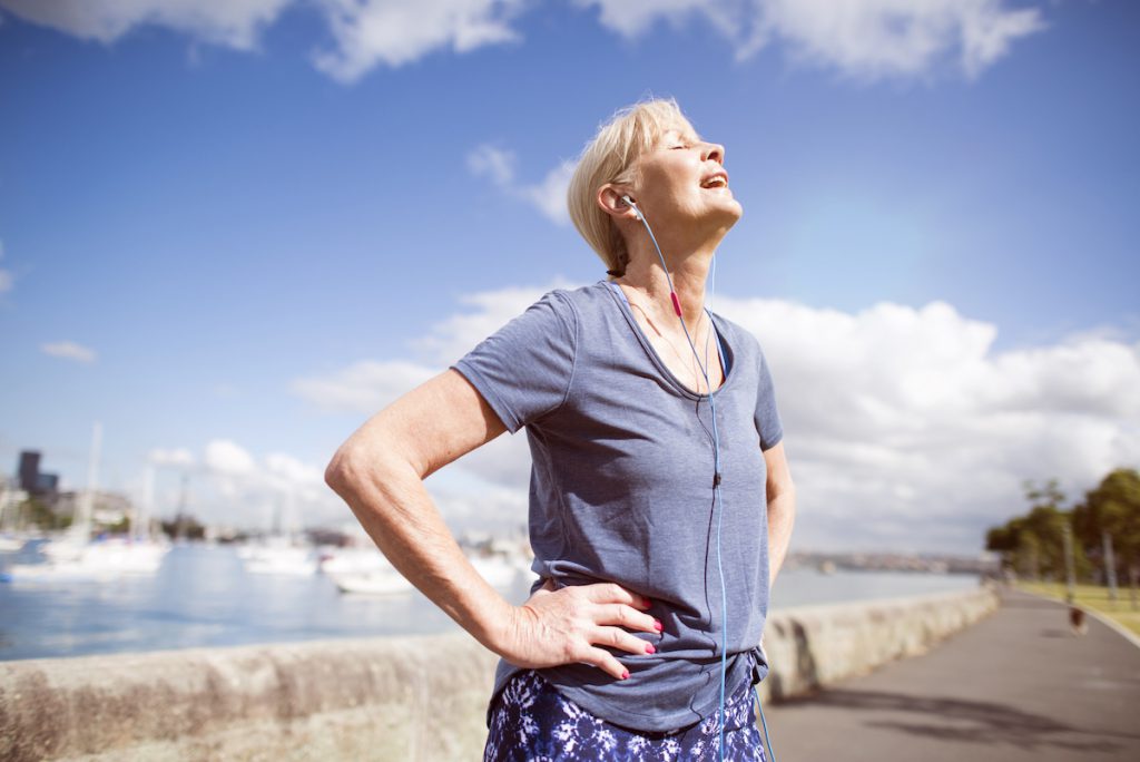 mature woman exercising outdoors looking happy