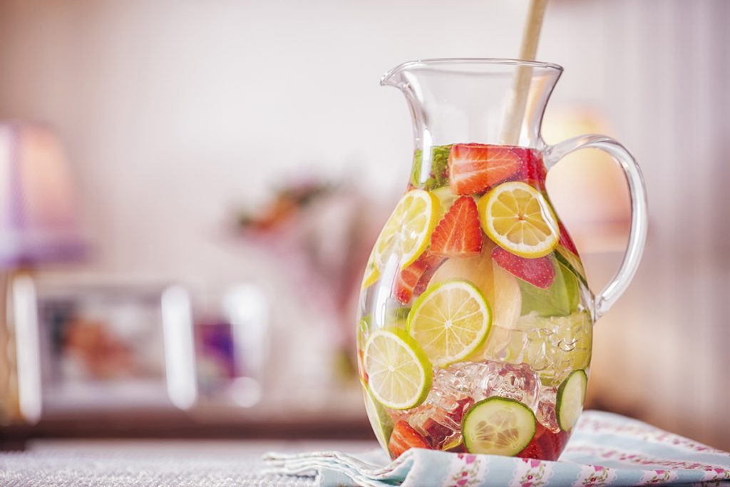 Infused water with fresh strawberries, lime, lemon and basil served in a glass.