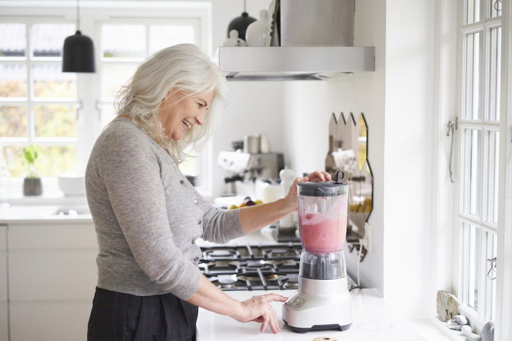 senior woman making a smoothie for a story on easy ways to eat more fiber