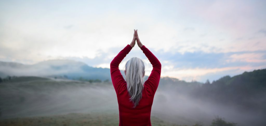 senior woman doing yoga outdoors for a story on yoga poses for better posture