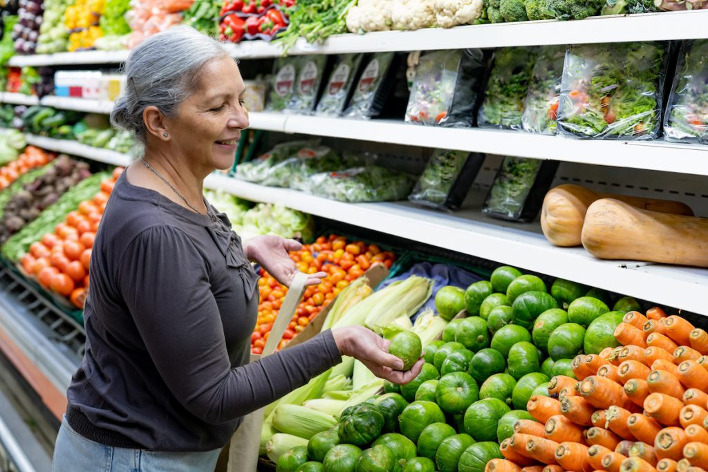 happy senior woman buying fresh vegetables for a story on the blue zone diet