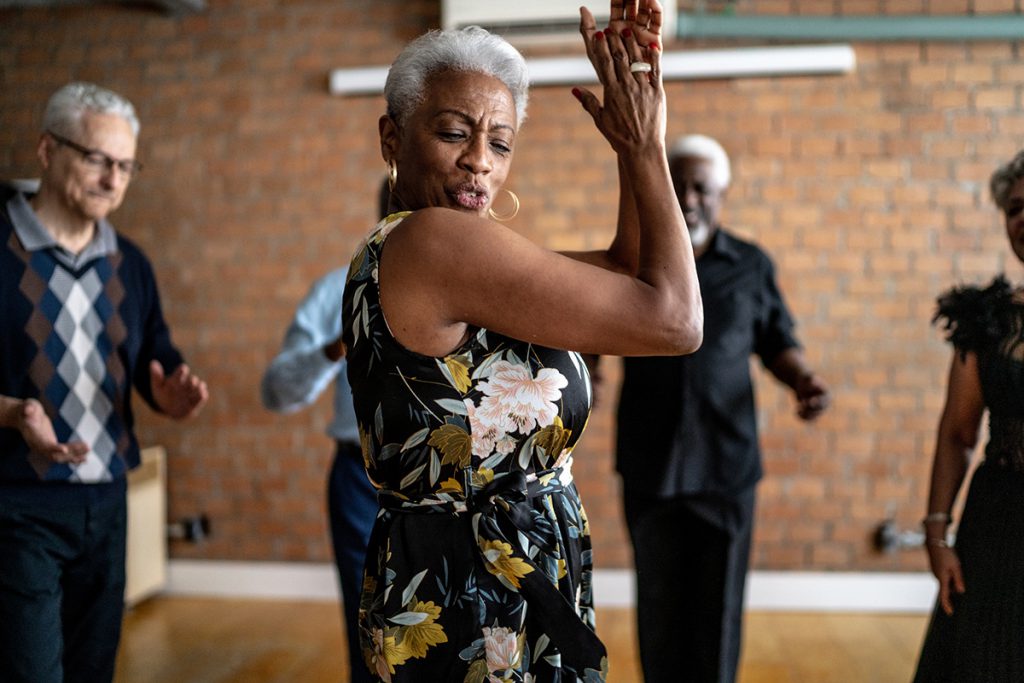 Older woman dancing with a group for a story on the benefits of belonging to a senior center