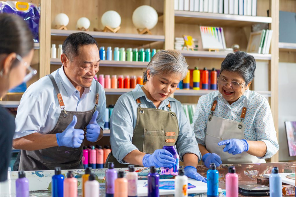 group of older friends taking an art class for a story on the happiness boost from lifelong learning