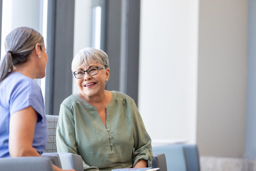 Senior woman smiling talking to a doctor for a story on what is a geriatrician doctor