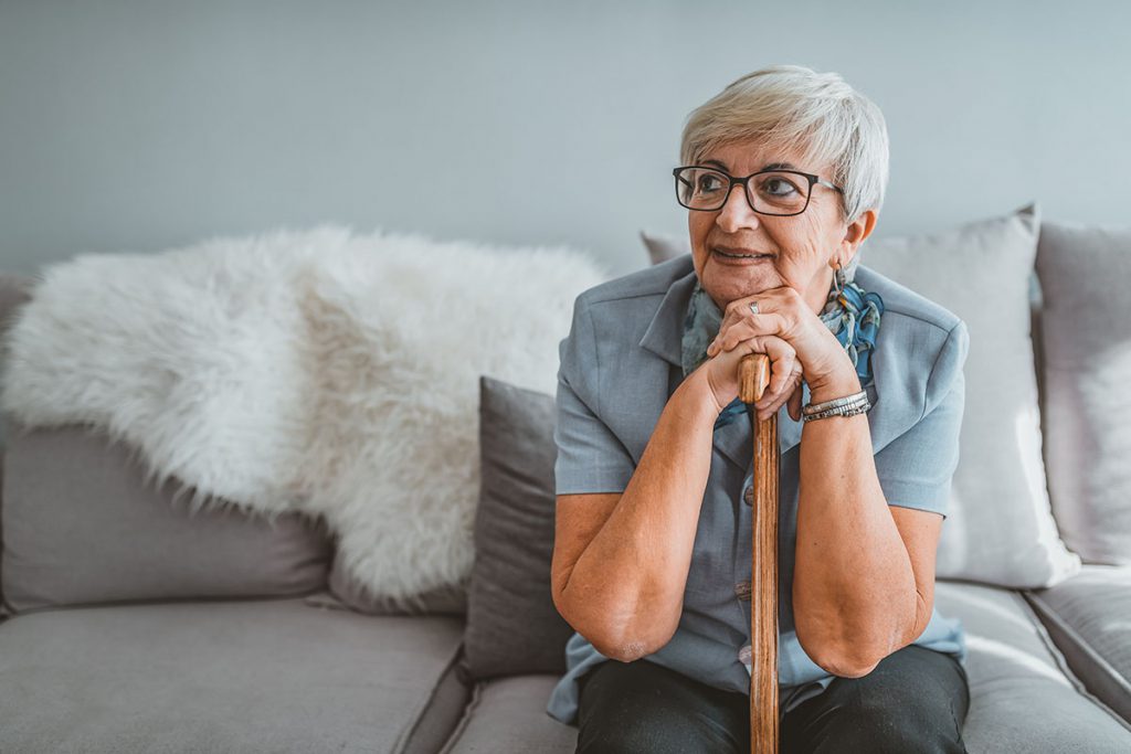 Happy senior woman sitting on her couch for a story on home modifications to age in place