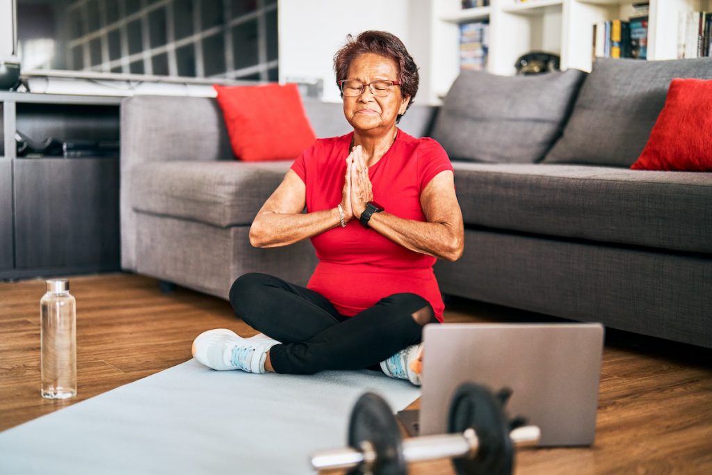 senior woman doing yoga at home for a story on the calming benefits of yoga for seniors