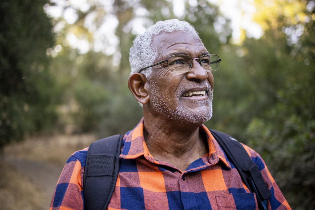 senior Black man wearing glasses out for a hike