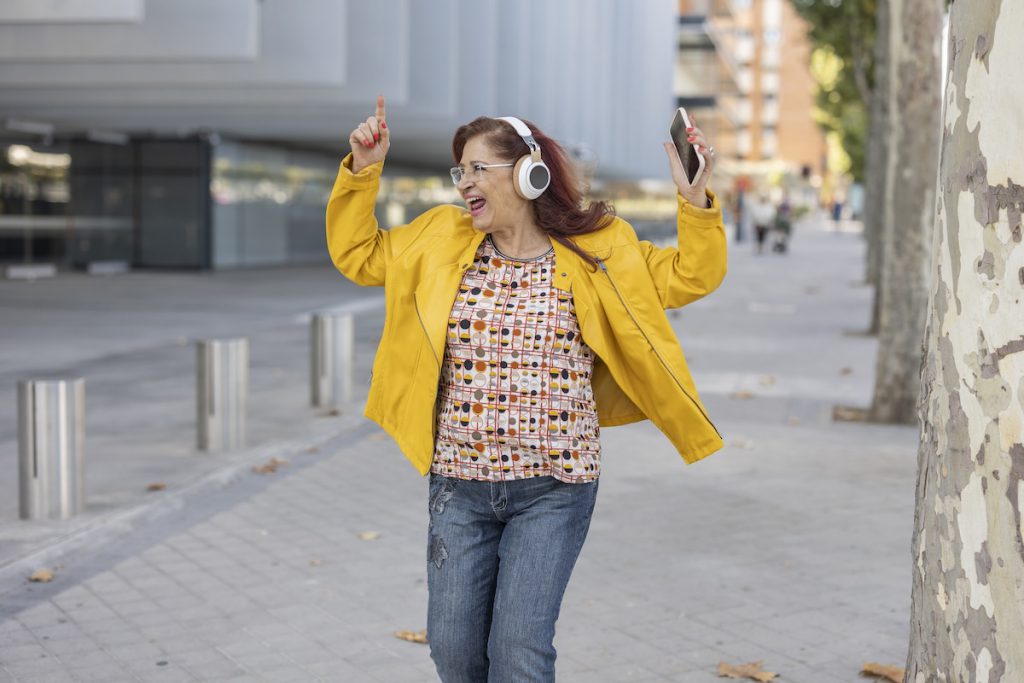 happy mature woman dancing in the street for a story on self-care